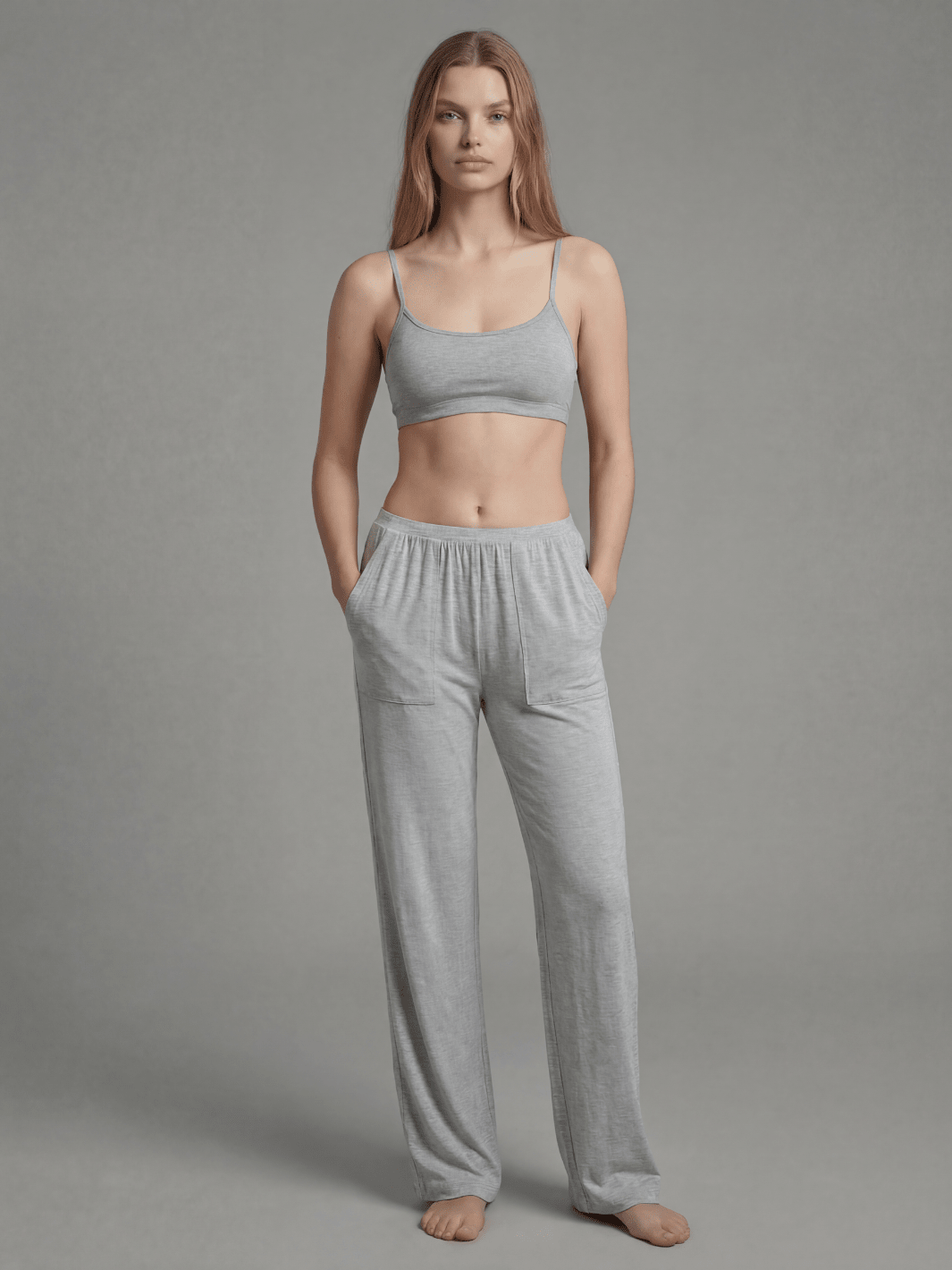 Woman wearing a gray sports bra and pants on a plain background