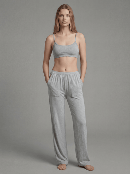 Woman wearing a gray sports bra and pants on a plain background