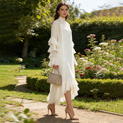 Woman in a white dress standing in a garden with flowers and greenery.